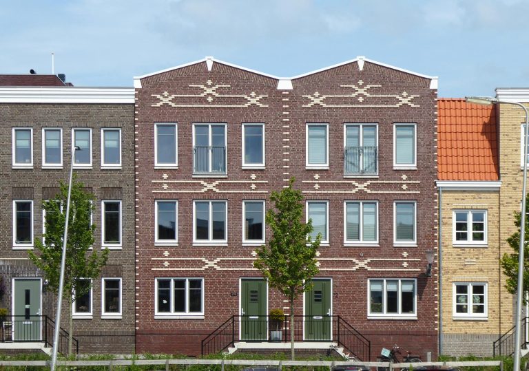 A row of houses with windows and a green lawn